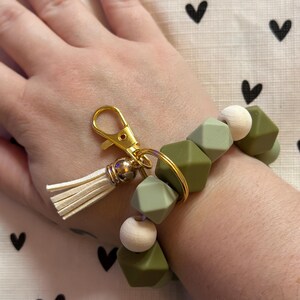 Llavero de pulsera con cuentas de madera, cuentas de silicona verde y cierre de mosquetón.
