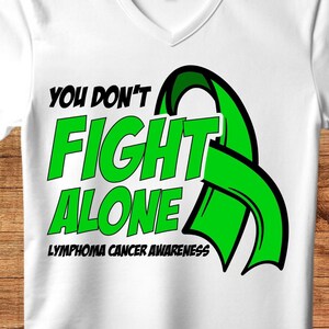 Könnte beinhalten: Weißes T-Shirt mit einem grünen Band und dem Text "You Don't Fight Alone" in Schwarz und Grün. Der Text "Lymphoma Cancer Awareness" ist ebenfalls in Schwarz enthalten.