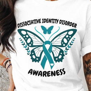 May include: White t-shirt with a teal butterfly and ribbon design. The text "Dissociative Identity Disorder Awareness" is printed on the shirt.