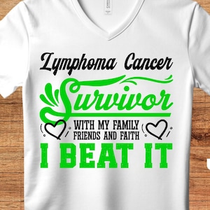 Könnte beinhalten: Weißes T-Shirt mit einer grünen und schwarzen Grafik, auf der "Lymphoma Cancer Survivor" mit einem Herzen und dem Text "With my family, friends and faith" und "I beat it" steht.