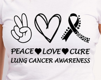 Puede incluir: Camiseta blanca con un signo de paz negro, un corazón y una cinta con el texto "Peace Love Cure Lung Cancer Awareness".