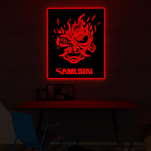 Könnte beinhalten: Ein rotes Neon-Schild mit einem Samurai-Masken-Design und dem Wort "SAMURAI" in Rot. Das Schild ist an einer dunklen Wand über einem roten Schreibtisch angebracht. Der Raum ist schwach beleuchtet, mit einem blauen Stuhl im Vordergrund.