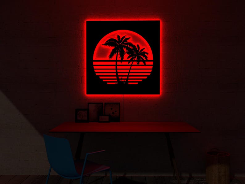 May include: A red neon sign with a black square featuring a tropical sunset scene with palm trees. The sign is mounted on a dark brick wall above a red desk. The room is dimly lit.