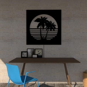 May include: Black metal wall art featuring a tropical sunset scene with palm trees and a sun. The artwork is mounted above a wooden desk with a blue chair. Several framed photos are on the desk, and a woven basket sits nearby.