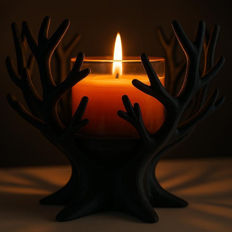 May include: A black, tree-shaped candle holder with a lit orange candle inside a glass. The candle flame is bright against the dark background. The holder has a detailed, antler-like design.