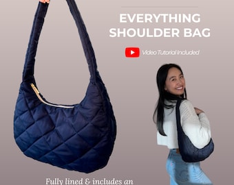 May include: A PDF sewing pattern for an Everything Shoulder Bag. The bag is dark navy blue with a quilted diamond pattern, a single shoulder strap, and a top zipper. Text includes PDF SEWING PATTERN, EVERYTHING SHOULDER BAG, and Video Tutorial Included.