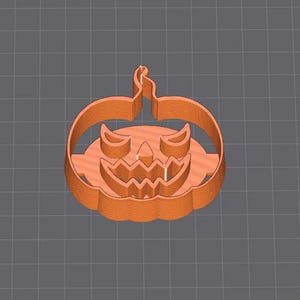 Puede incluir: Cortador de galletas de calabaza de plástico naranja con una cara de calabaza tallada.