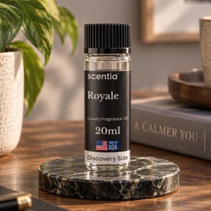 Op de afbeelding: Een doorzichtige glazen fles met Scentia Royale luxe geurolie en een zwarte geribbelde dop. Het zwarte etiket bevat witte tekst met Scentia, Royale, Luxury Fragrance Oil, 20ml, een kleine Amerikaanse vlag en Discovery Size.