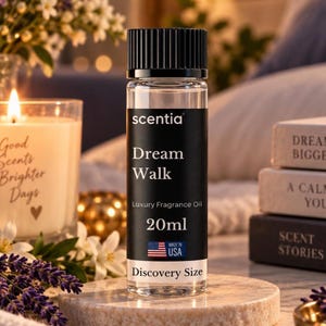 May include: A clear glass bottle of Scentia Dream Walk luxury fragrance oil with a black cap. The black label features white text reading Scentia, Dream Walk, Luxury Fragrance Oil, 20ml, Discovery Size, and a small American flag icon.
