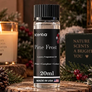 May include: A clear glass bottle of Scentia Pine Frost luxury fragrance oil with a black ribbed cap. The black label features white text reading Pine Frost, Luxury Fragrance Oil, Pine, Camphor, Cedar, 20ml, and MADE IN USA with a small flag icon.