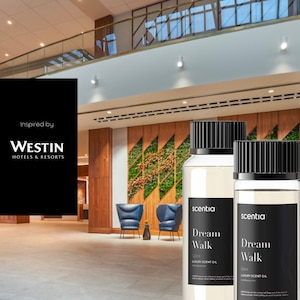 以下が含まれることがあります： 黒い蓋とラベルが付いた透明なガラス瓶が2本。瓶には透明な液体が入っており、「scentia Dream Walk」と「Luxury Scent Oil」の文字と、ミリリットル単位の容量が書かれたラベルが貼られています。瓶は緑色の壁と木製の枠の前に置かれています。