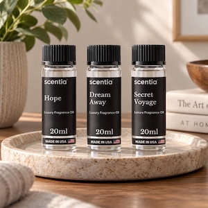May include: Three clear glass bottles of Scentia luxury fragrance oil, each with a black cap and a black label. The labels are printed with the text Hope, Dream Away, and Secret Voyage, along with 20ml and Made in USA with a small American flag.