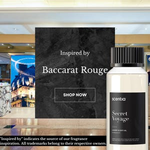 Könnte beinhalten: Eine durchsichtige Glasflasche mit schwarzem Verschluss und einem Etikett mit der Aufschrift "scentia Secret Voyage 50ml LUXURY SCENT OIL". Die Flasche steht auf einer schwarz-weißen, strukturierten Oberfläche. Der Text "Inspired by Baccarat Rouge" ist über der Flasche zu sehen.