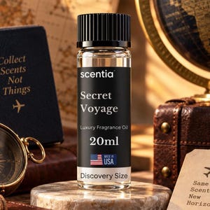 May include: A clear glass bottle of Scentia Secret Voyage fragrance oil with a black ribbed cap. The black label features white text reading Scentia, Secret Voyage, Luxury Fragrance Oil, 20ml, Discovery Size, and a small American flag icon.