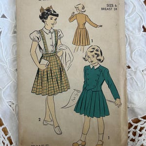 May include: Vintage sewing pattern titled "ADVANCE 5270" featuring illustrations of girls' dresses. The cover is aged with illustrations of a plaid jumper, a pleated skirt suit, and a long-sleeved jacket. The size is 6, with a 24-inch bust.