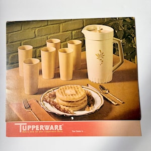 Könnte beinhalten: Ein Vintage-Werbedruck von Tupperware mit einem beigen Krug mit Blumenmuster, fünf passenden Bechern und einem Teller mit Waffeln und Speck. Das rote Banner unten zeigt den Text TUPPERWARE Make a date for your Tupperware Party.