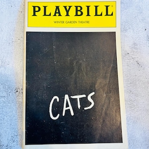 May include: A Playbill from the Winter Garden Theatre with a yellow header. The word "PLAYBILL" is printed in black capital letters. The title "CATS" is written in white on a black background.