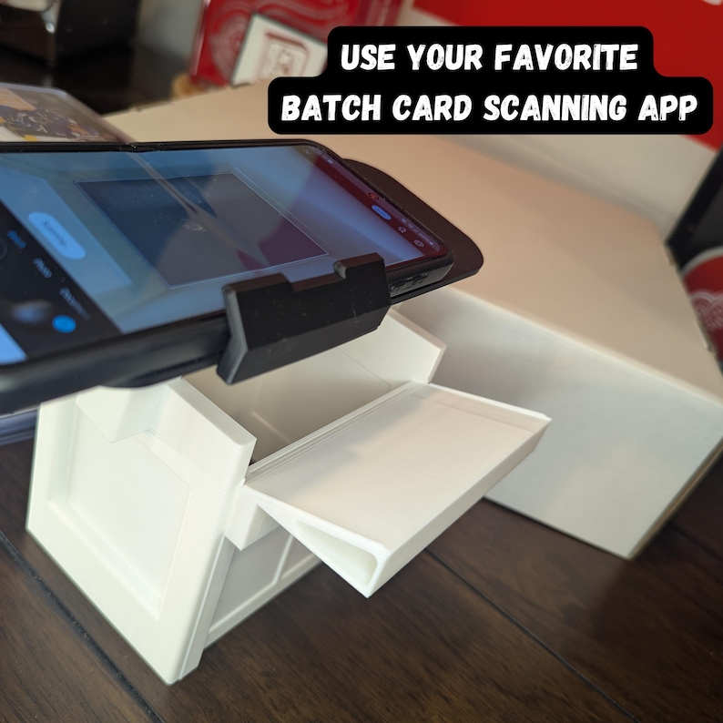 K&ouml;nnte beinhalten: Wei&szlig;e Kartenscan-Station mit einem Smartphone in einem schwarzen Etui, das oben befestigt ist. Das Telefon zeigt eine Kartenscan-App an. Der Text auf der wei&szlig;en Box lautet "USE YOUR FAVORITE BATCH CARD SCANNING APP".