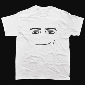 May include: White t-shirt with a black cartoon face design. The graphic shows eyes, eyebrows, and a smiling mouth. The shirt is made of a soft material and has short sleeves.