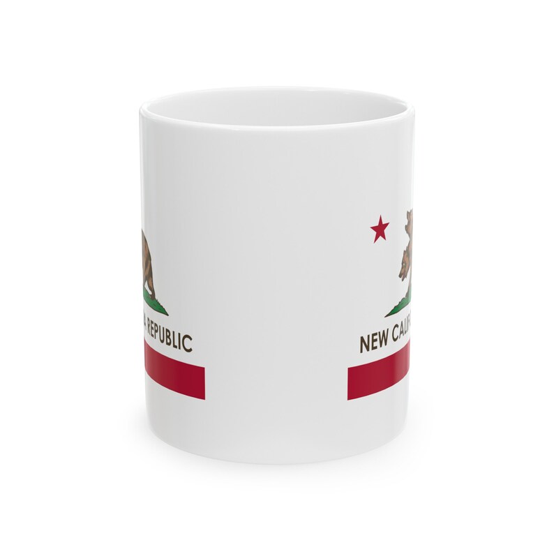 May include: White ceramic mug featuring the California Republic flag design. The flag includes a brown bear, green grass, a red star, and a red stripe at the bottom. The words "NEW CAL" and "REPUBLIC" are also visible.