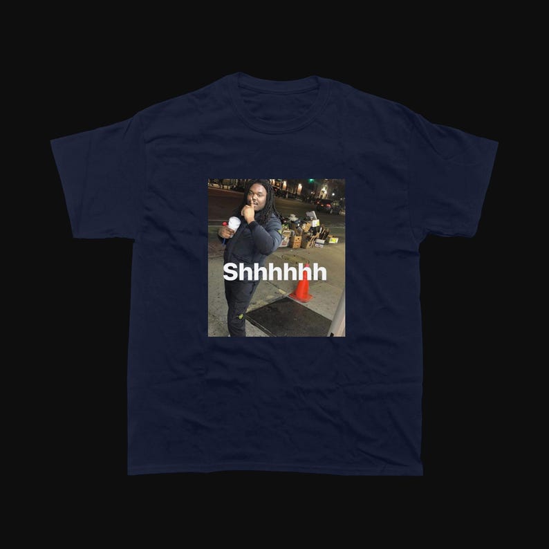 Op de afbeelding: Marineblauw T-shirt met een meme van een persoon die een beker vasthoudt en het woord "Shhhhhhh" op de afbeelding. De afbeelding is vierkant en gecentreerd op het shirt.