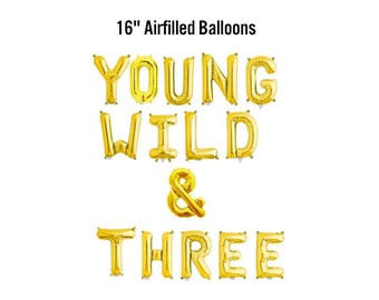 May include: Gold foil balloons spelling out "YOUNG WILD & THREE" on a white background. The balloons are 16 inches in size and are airfilled. Perfect for a third birthday celebration.