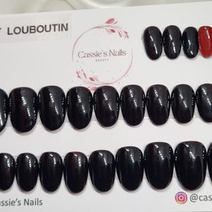 May include: A collection of glossy, dark burgundy press-on nails in different sizes, with one red nail. The text "EFFET LOUBOUTIN" is at the top. The Cassie's Nails logo and social media handles are at the bottom.