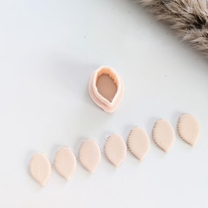May include: A set of eight pale pink leaf-shaped polymer clay pieces, arranged in a row, with a single leaf-shaped mold in the center.