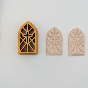 May include: Three stained glass window-shaped ornaments, two are white and one is gold. The gold ornament is a cookie cutter and the white ornaments are finished.