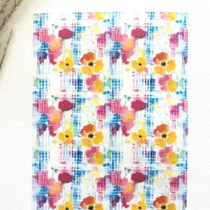 May include: A seamless pattern featuring watercolor-style flowers in shades of pink, yellow, and orange. The flowers are set against a background of blue and pink abstract brushstrokes.