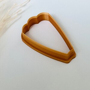 May include: A brown plastic cookie cutter shaped like a tulip.