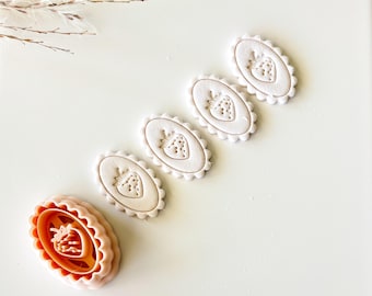 May include: A collection of strawberry-shaped cookie cutters and stamped biscuits. The cutters are pink and orange, while the biscuits are beige. The biscuits have an oval shape with a scalloped edge and a strawberry design in the centre.