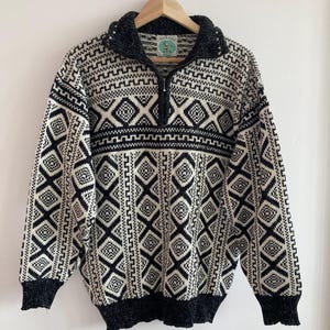 Può includere: Maglione a motivi bianco e nero con chiusura a mezzo zip. Il maglione ha un collo e polsini grigio scuro. L'etichetta del marchio recita "Gala Kids".