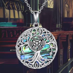May include: A silver necklace with a round pendant featuring a tree of life design with a blue and green abalone shell inlay. The pendant also includes a silver Celtic knot design.