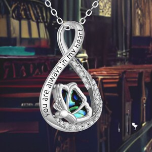 May include: Silver infinity necklace with a butterfly charm and the inscription "You are always in my heart".