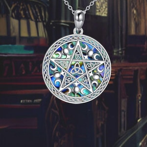 Puede incluir: Collar con colgante de plata con un pentagrama con un diseño de nudo celta y un patrón de fase lunar. El colgante está hecho de concha de abulón y tiene un acabado azul, verde e iridiscente.