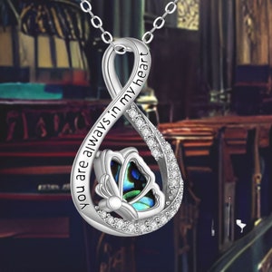 May include: Silver infinity necklace with a butterfly charm and the inscription "You are always in my heart".