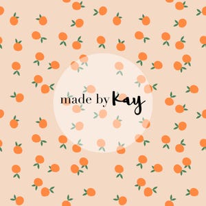 Op de afbeelding: Een perzikkleurige achtergrond met een herhalend patroon van oranje cirkels met groene bladeren. De tekst "made by Kay" staat in het midden van de afbeelding.
