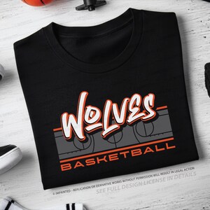 Könnte beinhalten: Schwarzes T-Shirt mit dem Wort "WOLVES" in weißer und orangefarbener Schrift. Darunter ein graues Basketballfeld-Design mit dem Wort "BASKETBALL" in orangefarbener Schrift. Rundhalsausschnitt.