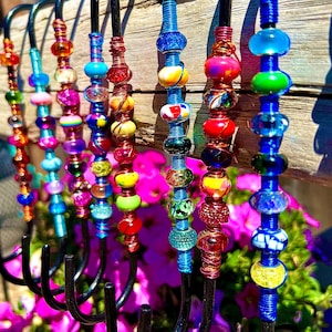 May include: A set of 10 colorful beaded hooks, each with a different pattern of beads. The hooks are made of black metal and are perfect for hanging items on a wall.