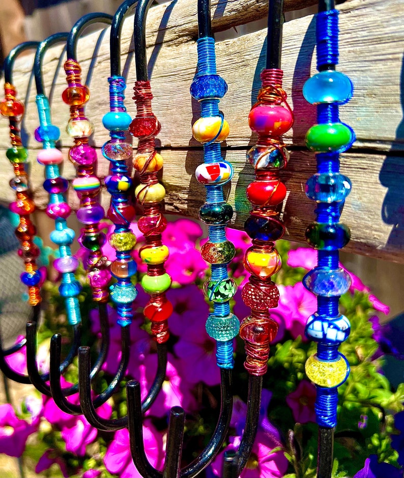 May include: A set of 10 colorful beaded hooks, each with a different pattern of beads. The hooks are made of black metal and are perfect for hanging items on a wall.