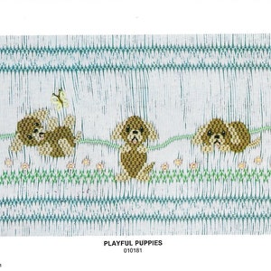 May include: A white embroidery pattern with three brown puppies and a butterfly. The pattern is titled "Playful Puppies" and the number 010181 is printed below the title. The copyright information "1986 Ellen McCarn" is printed at the bottom left corner of the pattern and "Printed in U.S.A." is printed at the bottom right corner.