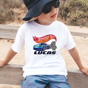 Racing Car Birthday Boy Shirt featuring a red and yellow banner that says Birthday Boy, blue race car, custom name, and custom age in black and white checkered print