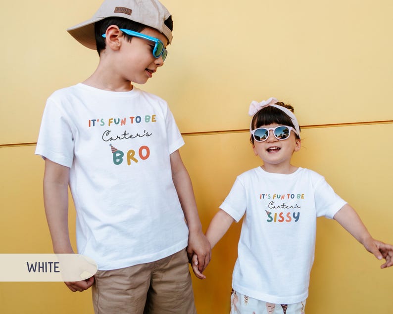 May include: Two children in white t-shirts with the text "IT'S FUN TO BE Carter's BRO" and "IT'S FUN TO BE Carter's SISSY" in colourful letters. The boy wears a cap and sunglasses, and the girl wears sunglasses and a headband.