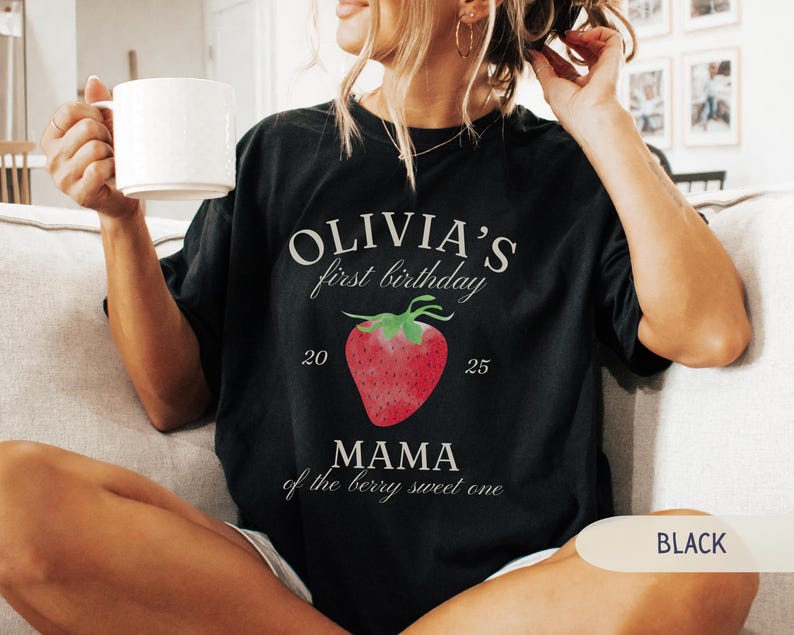 May include: Black t-shirt with the text "OLIVIA'S first birthday" above a red strawberry graphic. Below the strawberry is the text "MAMA of the berry sweet one". The numbers "20" and "25" are on either side of the strawberry.