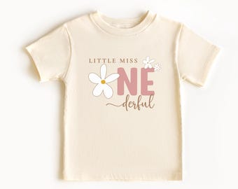May include: A cream colored t-shirt with a pink and white graphic that says "Little Miss One-derful" with a daisy and a pink number one.