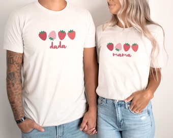 May include: White t-shirts with red strawberries and the words "dada" and "mama" printed on them.