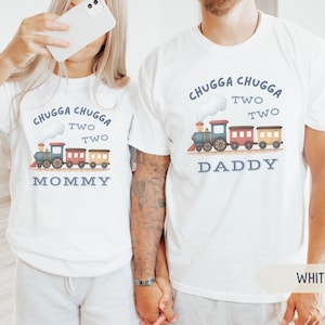 May include: White t-shirts with a train graphic and the text "Chugga Chugga Two Two." One shirt says "Mommy" and the other says "Daddy." The train is blue, red, and yellow.