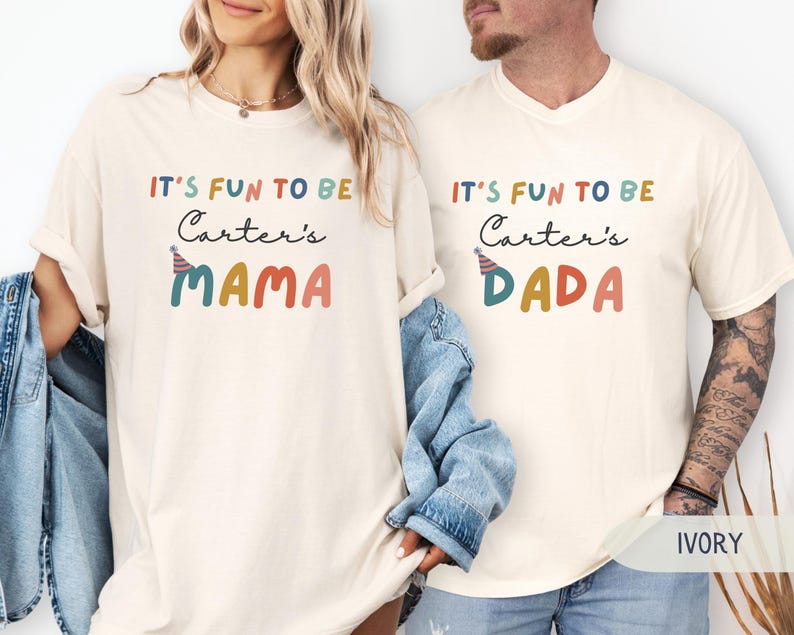 May include: Ivory-coloured t-shirts with the text "IT'S FUN TO BE Carter's MAMA" and "IT'S FUN TO BE Carter's DADA" in colourful lettering. The shirts have a relaxed fit and short sleeves. The word "IVORY" is printed at the bottom.
