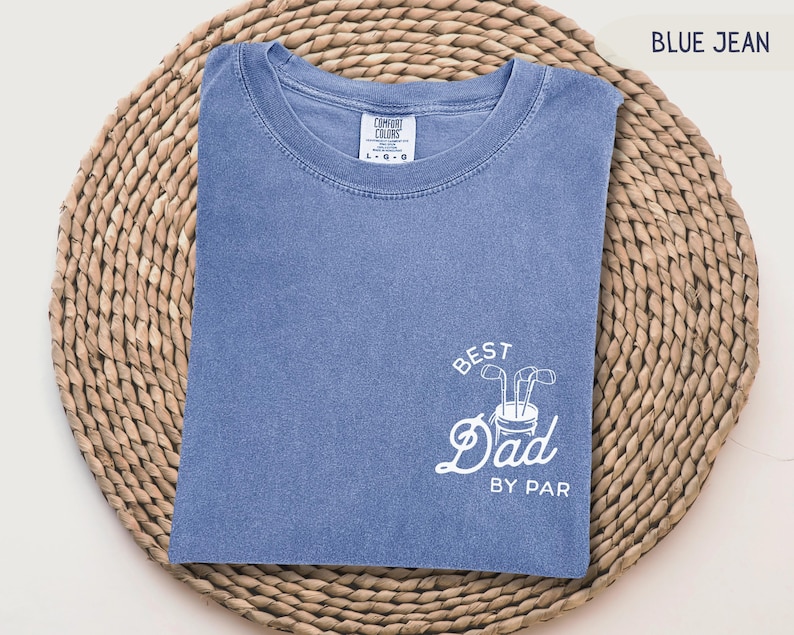May include: A blue jean t-shirt with white text that says "Best Dad By Par" and a graphic of a golf bag with clubs.